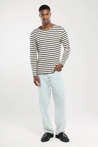 Man wearing a navy and white striped long-sleeve shirt with light blue jeans and black shoes