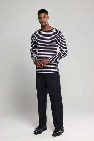 Man wearing navy and white striped long sleeve shirt with black trousers