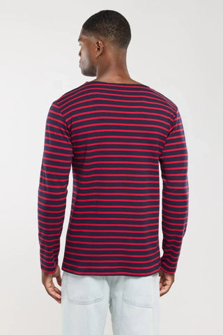 Man wearing navy and red striped long sleeve shirt, seen from the back, with light jeans