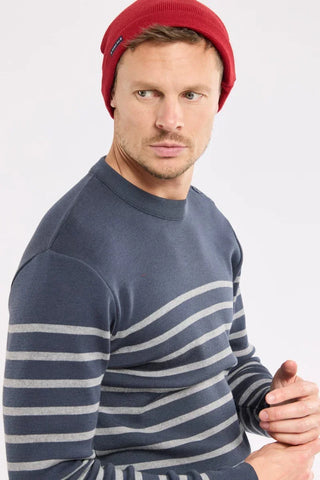 Man in a blue striped sweater and red knit beanie looking sideways