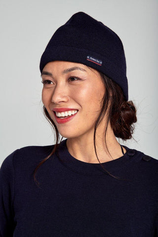 Smiling woman wearing a navy wool Breton beanie and navy knit sweater