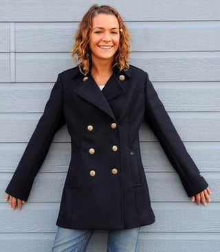 Woman wearing navy double-breasted pea coat with gold buttons, casual outdoor setting