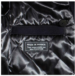 Close-up of a quilted black satin jacket lining with 'Made in France' label and buttoned pocket.