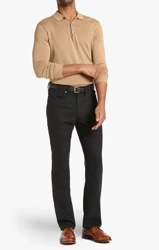 Man wearing brown feather tweed pants, beige polo, brown belt, and dress shoes