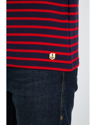Navy cotton Breton striped shirt with red stripes and anchor patch, paired with dark jeans