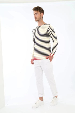 Man wearing long sleeve striped Breton shirt with red accents and white pants