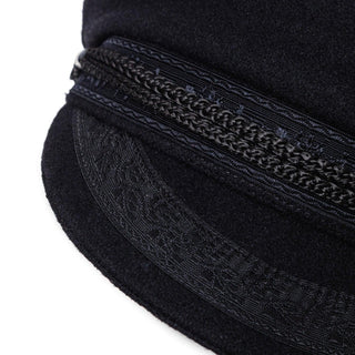 Close-up of a navy wool captain's hat with decorative braided trim and intricate embroidery.