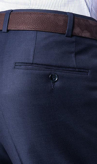 Close-up of navy wool dress pants with brown leather belt and back pocket button detail.