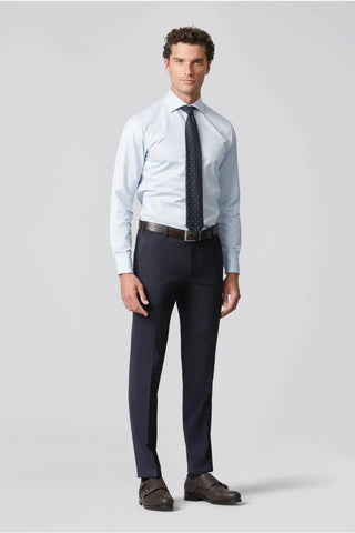 Man wearing light blue dress shirt, navy wool trousers, polka dot tie, and brown shoes