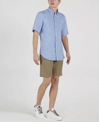 Man wearing light blue short-sleeve linen shirt, khaki shorts, and white sneakers